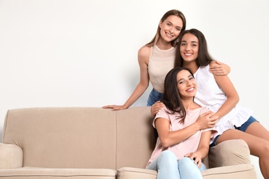 Happy women sitting on sofa near white wall, space for text. Girl power concept