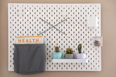 Photo of Pegboard with different cacti and magazine on wall