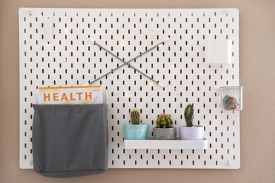 Pegboard with different cacti and magazine on wall