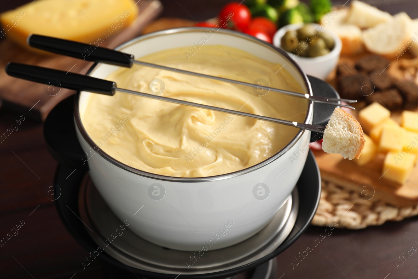 Photo of Fondue with tasty melted cheese, forks and piece of bread on table