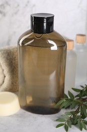 Photo of Shampoo bottle, essential oils, folded towel and solid shampoo bar on white marble table