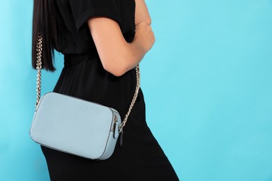 Photo of Woman with stylish bag on light blue background, closeup. Space for text