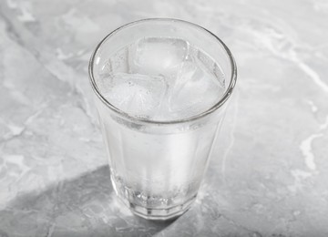 Photo of Glass of soda water with ice on grey table