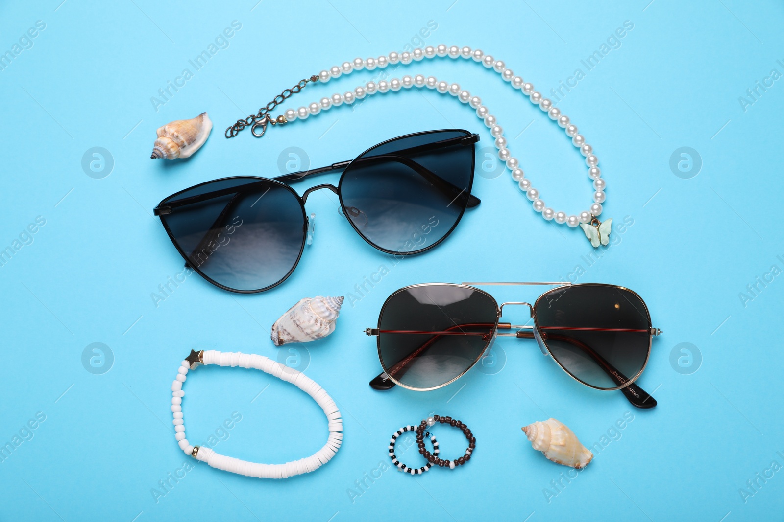Photo of Flat lay composition with stylish sunglasses, seashells and accessories on light blue background