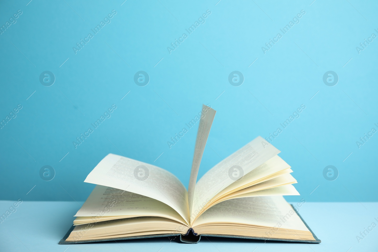 Photo of Open old hardcover book on light blue background