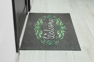 Photo of Doormat with word Welcome on white floor near entrance