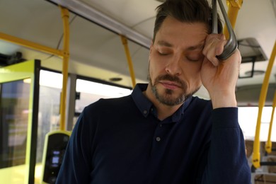 Tired man sleeping while riding in public transport