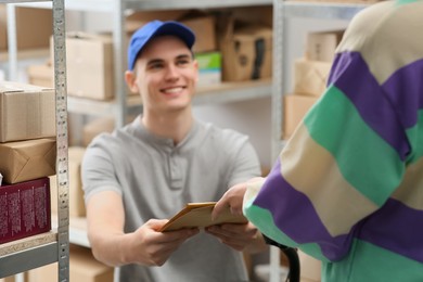 Worker giving parcel to woman at post office