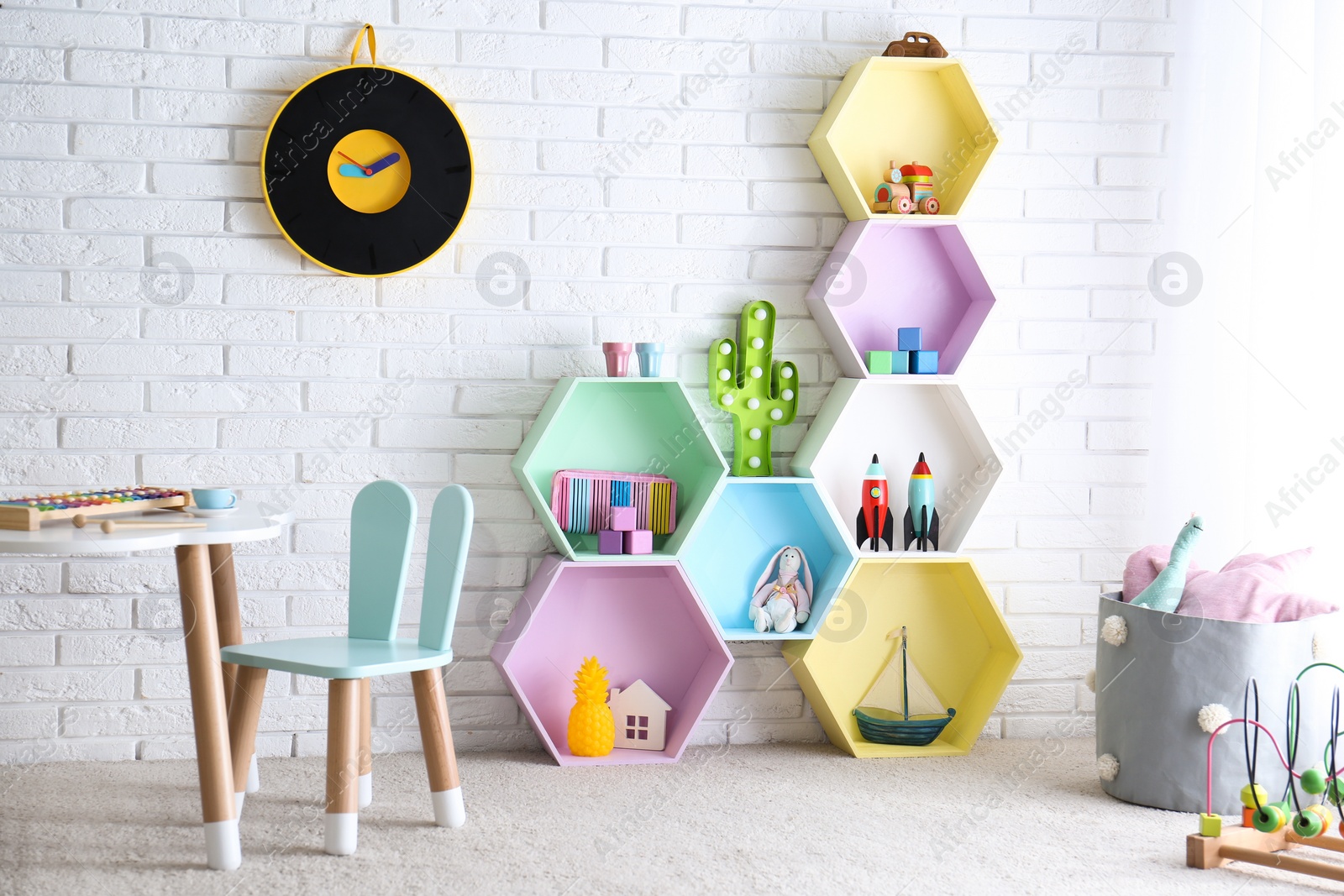 Photo of Child room interior with colorful shelves near brick wall