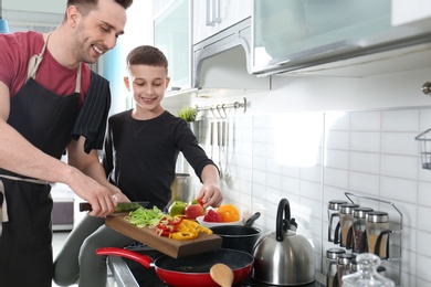 Photo of Dad and son cooking together in kitchen