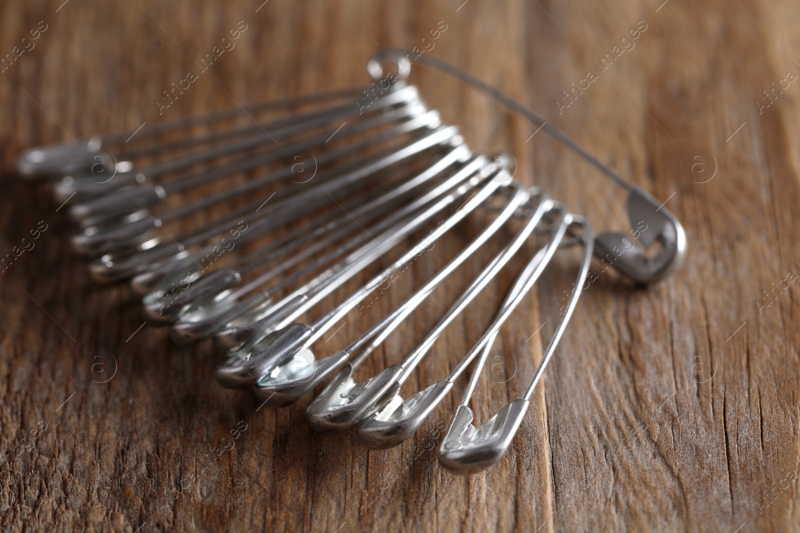 Photo of Many safety pins on wooden table, closeup