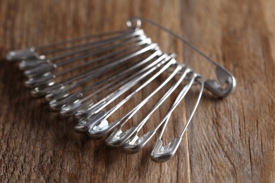 Many safety pins on wooden table, closeup