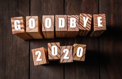 Blocks with phrase Goodbye 2020 on wooden table, above view