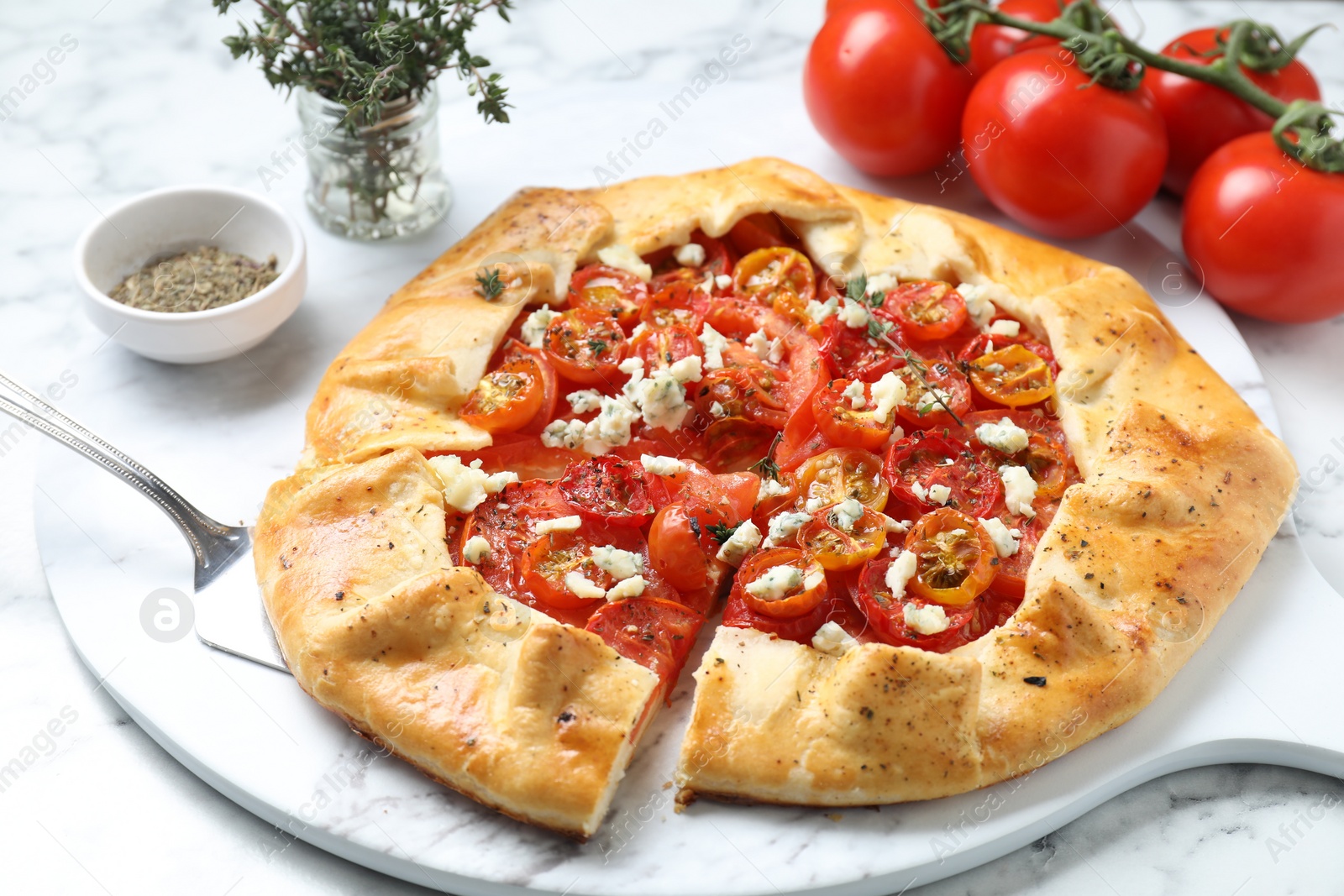 Photo of Tasty galette with tomato, thyme and cheese (Caprese galette) on white marble table, closeup