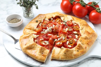 Photo of Tasty galette with tomato, thyme and cheese (Caprese galette) on white marble table, closeup