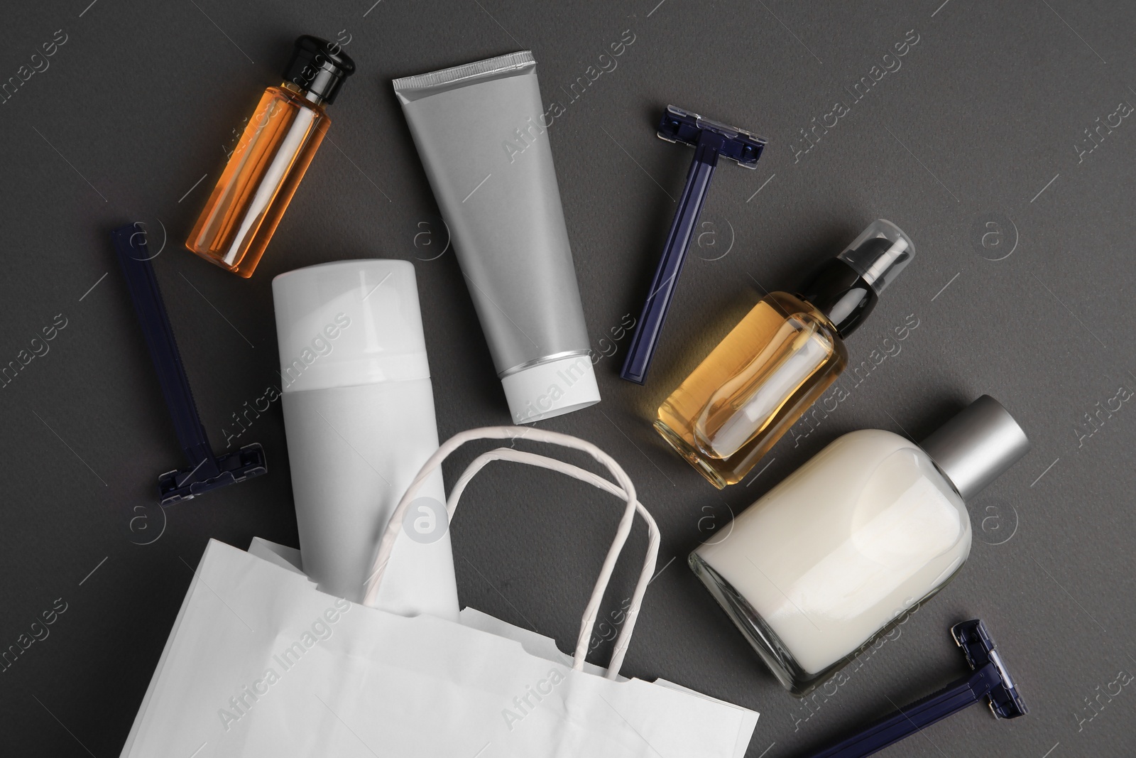 Photo of Different men's shaving accessories and paper bag on dark grey background, flat lay