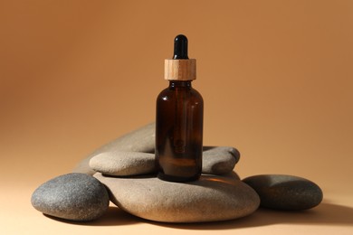 Photo of Bottle of face serum and spa stones on beige background