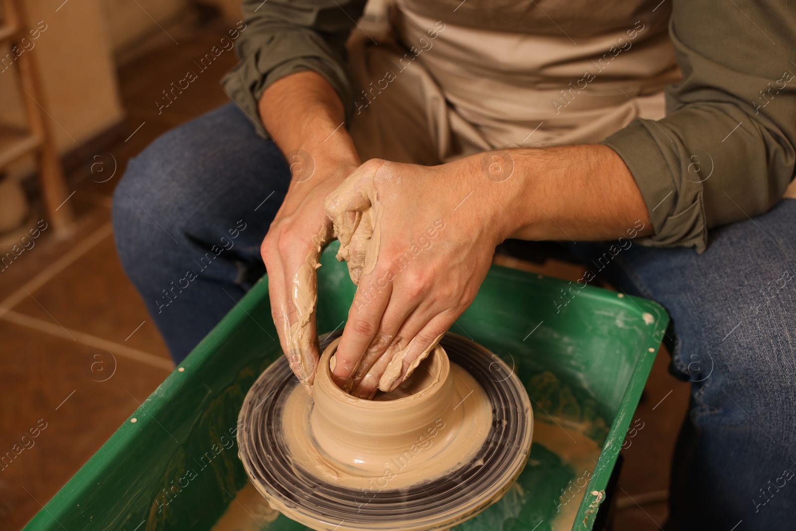 Photo of Clay crafting. Man making bowl on potter's wheel indoors, closeup