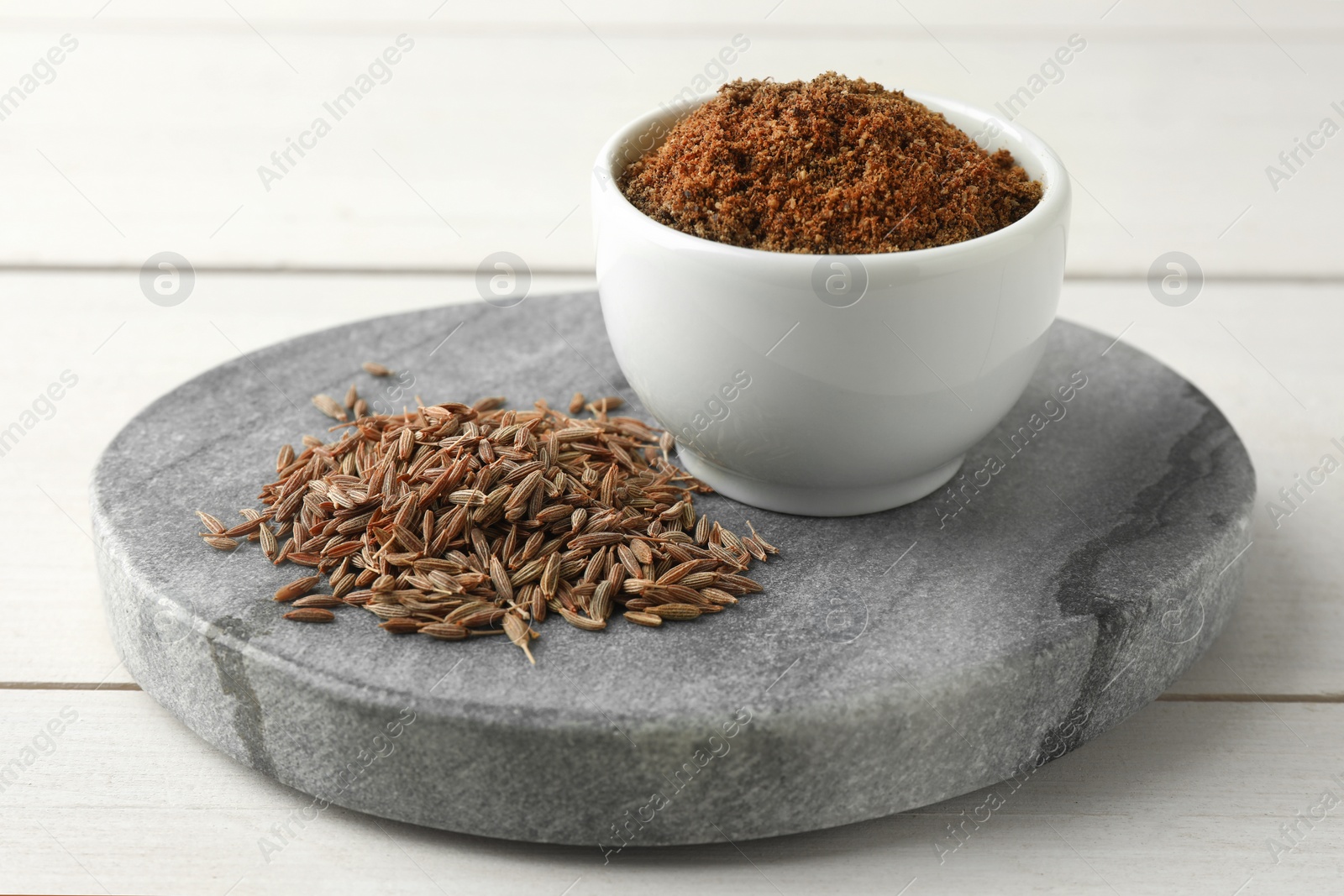 Photo of Caraway (Persian cumin) seeds and powder on white wooden table