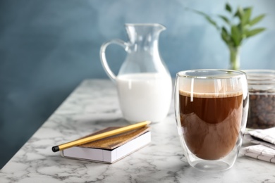 Glass of aromatic hot coffee on marble table