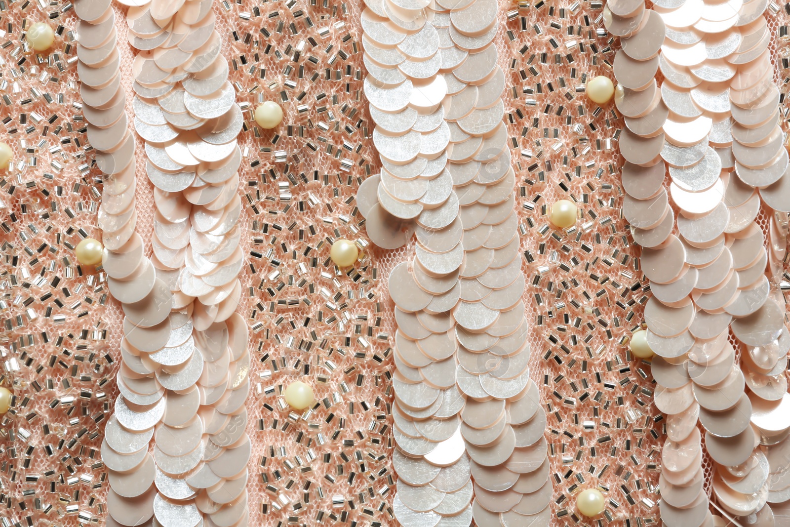 Photo of Closeup view of rose gold fabric with paillettes and beads as background