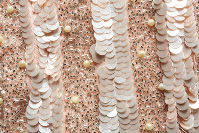 Closeup view of rose gold fabric with paillettes and beads as background