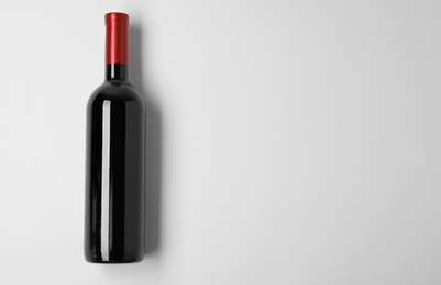 Bottle of expensive red wine on light background, top view