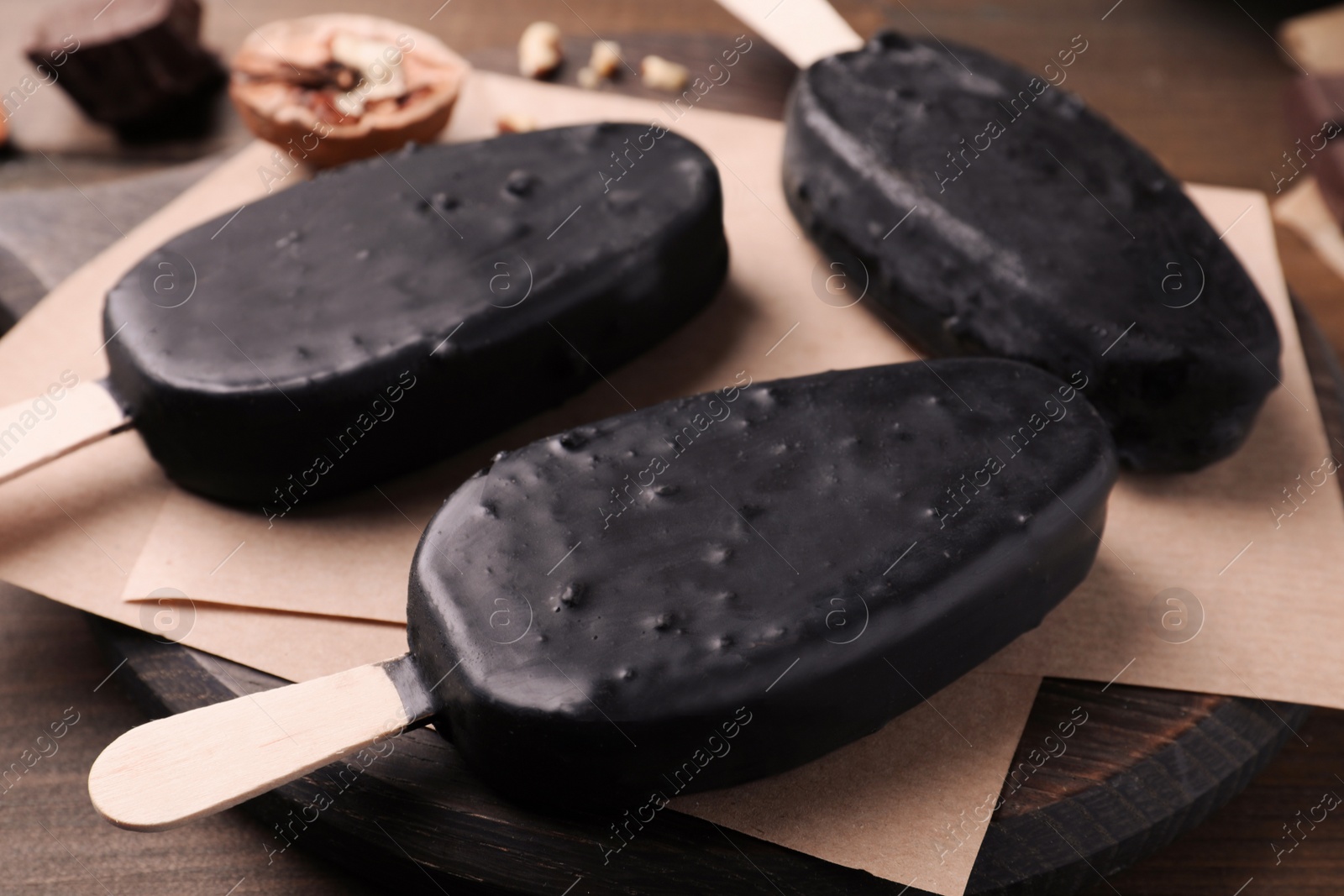 Photo of Delicious glazed ice cream bars on wooden board, closeup