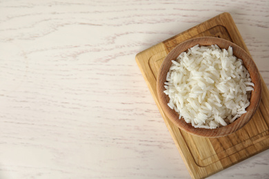 Photo of Bowl with cooked rice on white wooden table, flat lay. Space for text