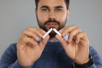 Stop smoking concept. Man breaking cigarette on light grey background, selective focus