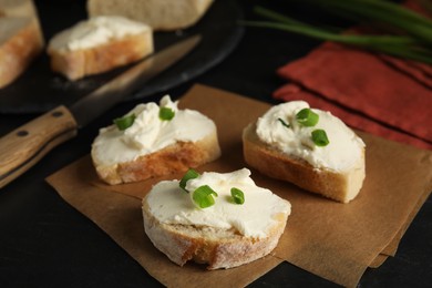 Photo of Bread with cream cheese and green onion on black table