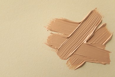 Photo of Sample of liquid skin foundation on beige background, top view. Space for text