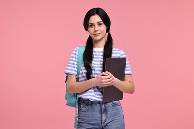 Photo of Cute student with laptop on pink background
