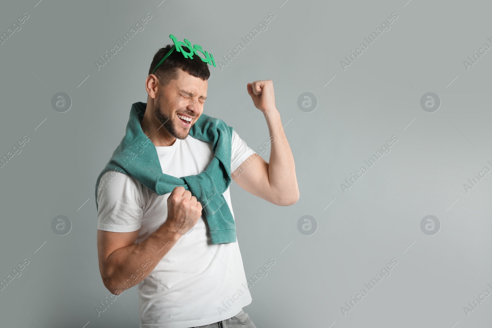 Photo of Happy man in St Patrick's Day outfit on light grey background, space for text