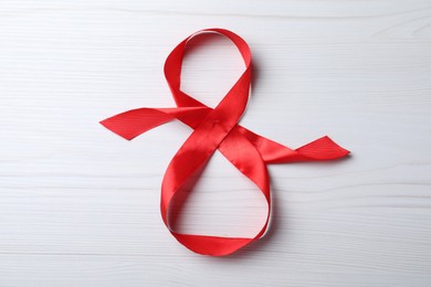 Photo of 8 March greeting card design with red ribbon on white wooden background, top view. International Women's day
