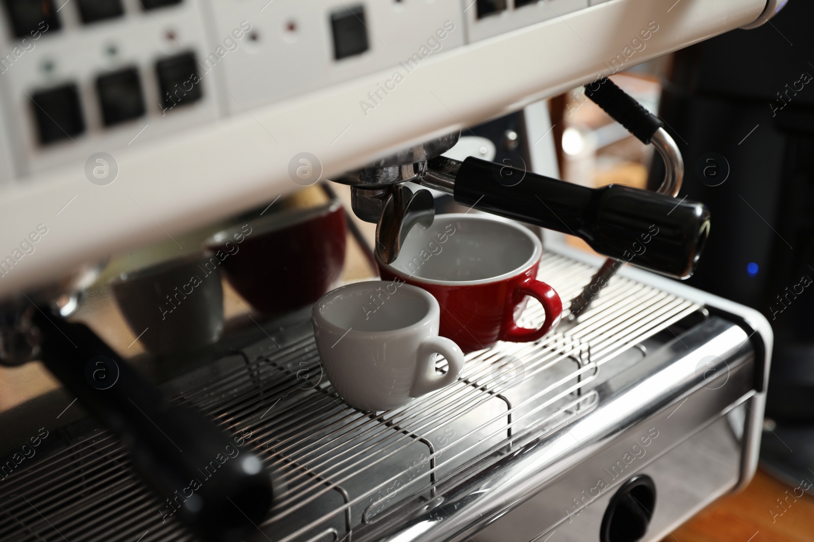 Photo of Modern coffee machine with cups in cafe