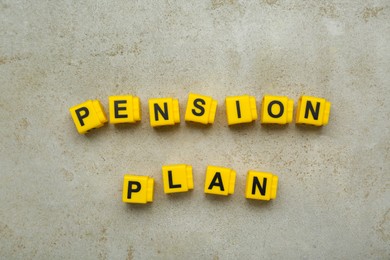 Photo of Words Pension Plan made of yellow cubes on light textured table, flat lay