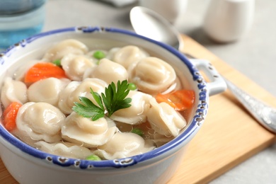 Photo of Bowl of tasty dumplings in broth on table, closeup. Space for text