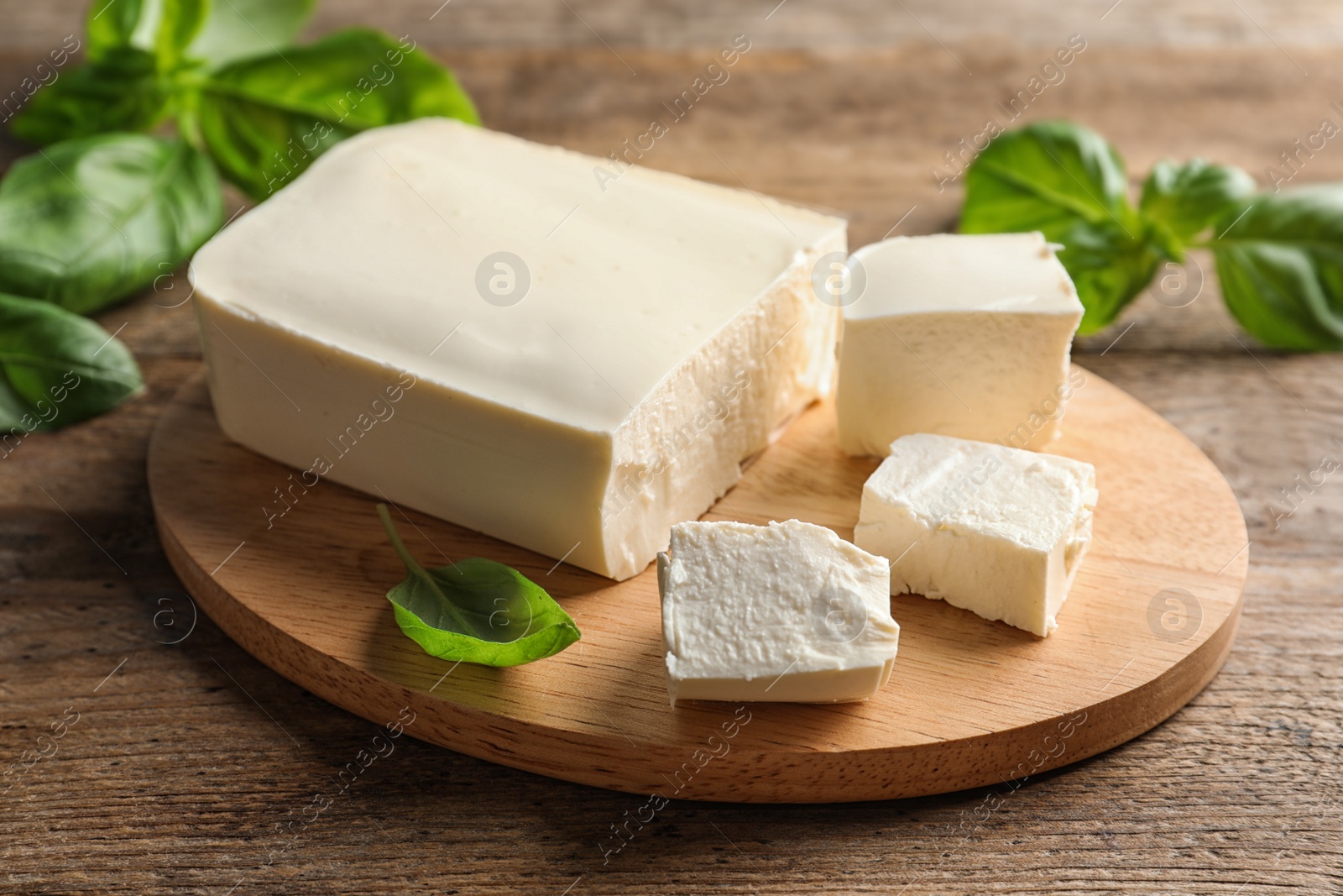 Photo of Board with feta cheese and basil on wooden table