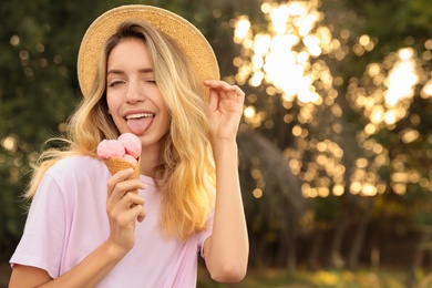 Happy young woman with delicious ice cream in waffle cone outdoors. Space for text