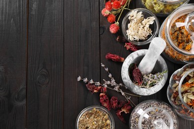 Mortar with pestle and many different herbs on wooden table, flat lay. Space for text