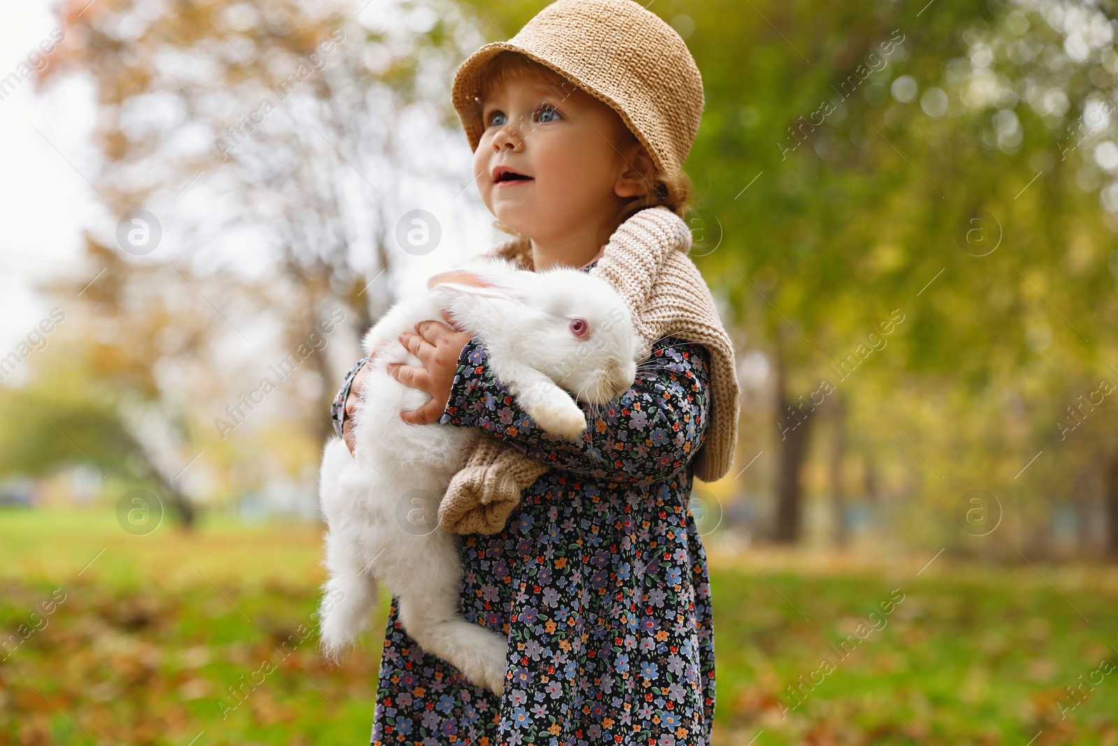 Photo of Girl walking with cute white rabbit in autumn park