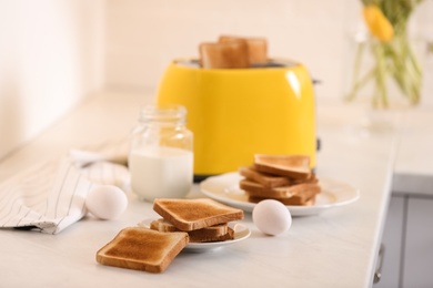 Modern toaster and delicious breakfast on table in kitchen