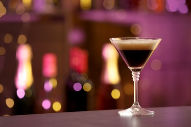 Photo of Glass of Espresso Martini on counter in bar, space for text. Alcohol cocktail