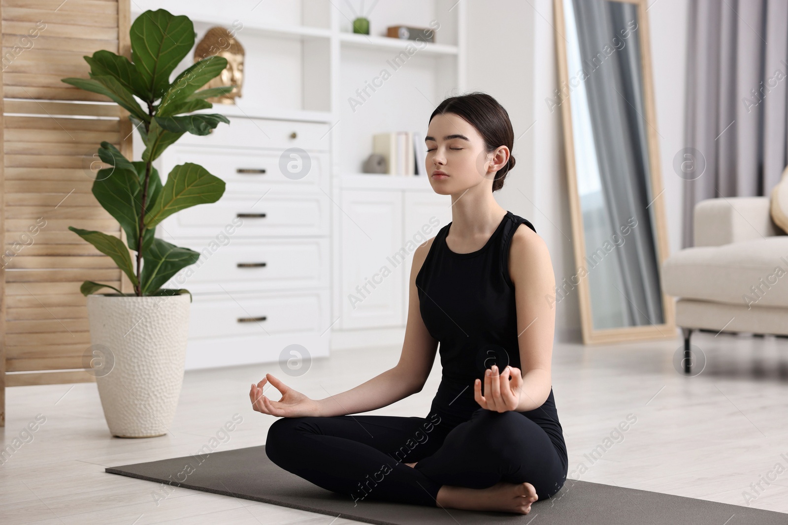 Photo of Beautiful girl meditating on yoga mat at home