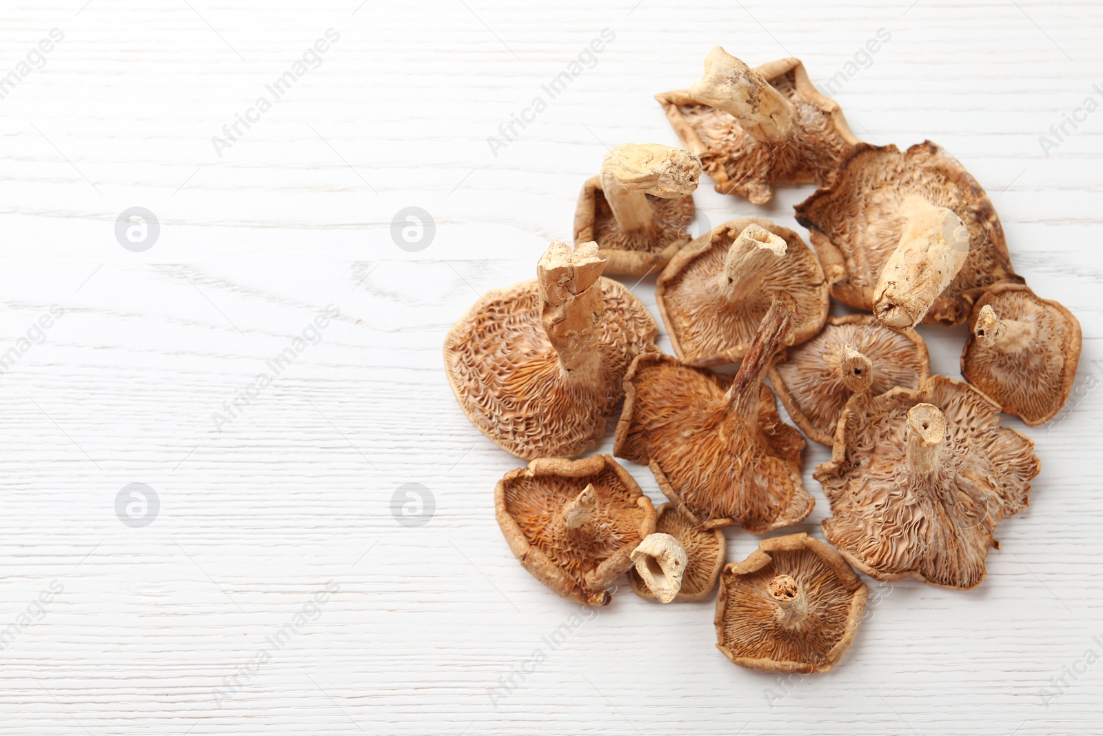 Photo of Dried mushrooms on wooden background, top view. Space for text