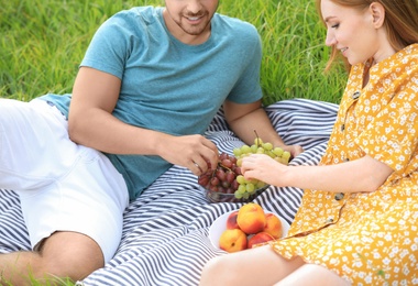 Photo of Happy young couple having picnic on green grass, closeup