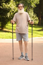Photo of Senior man with Nordic walking poles outdoors