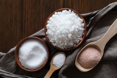 Photo of Different types of organic salt on wooden table, flat lay