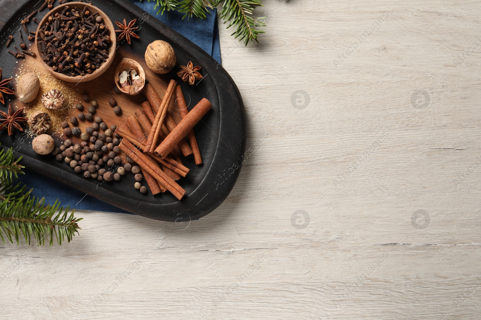 Photo of Different spices, nuts and fir branches on wooden table, flat lay. Space for text